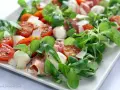 Pyszna sałatka z szynką parmeńską, pomidorkami koktajlowymi, mozzarellą i świeżą rukolą. Idealna na lekki posiłek.