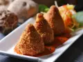 Złociste arancini, idealne do domowego arancini przepis, podane na talerzu z sosem pomidorowym i surówką.