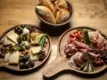 Deska serów i wędlin inspiracje: bogactwo smaków i aromatów na drewnianych deskach, z pieczywem w tle.