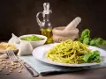 Pyszny makaron z pesto ze słoika, podany z bazylią, czosnkiem, parmezanem i orzeszkami pinii.