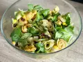 Kolorowa sałatka z tortellini, kukurydzą i suszonymi pomidorami w szklanej misce.