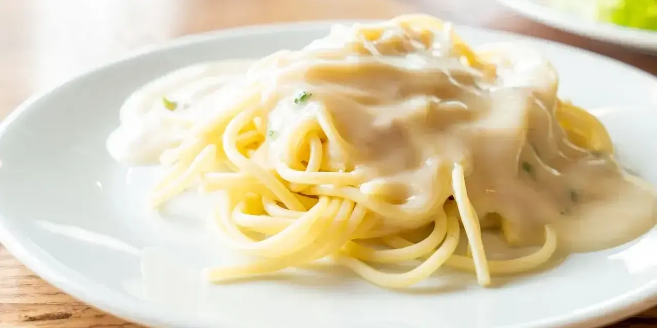 Pyszny makaron spaghetti polany kremowym sosem serowym, gotowy do podania.