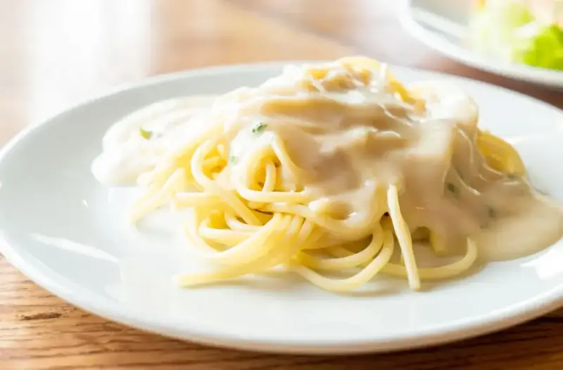 Pyszny makaron spaghetti polany kremowym sosem serowym, gotowy do podania.