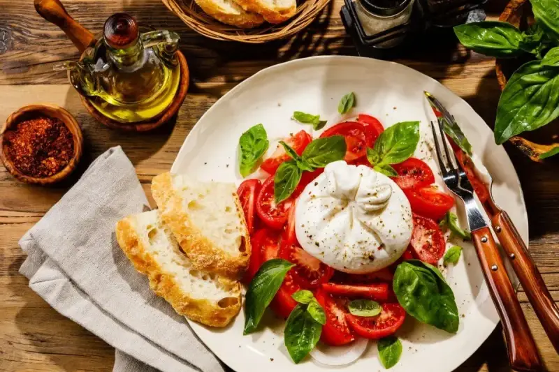 Pyszny **burrata przepis** na talerzu: kremowy ser, pomidory, bazylia i chrupiące pieczywo. Idealna propozycja na lekki posiłek.