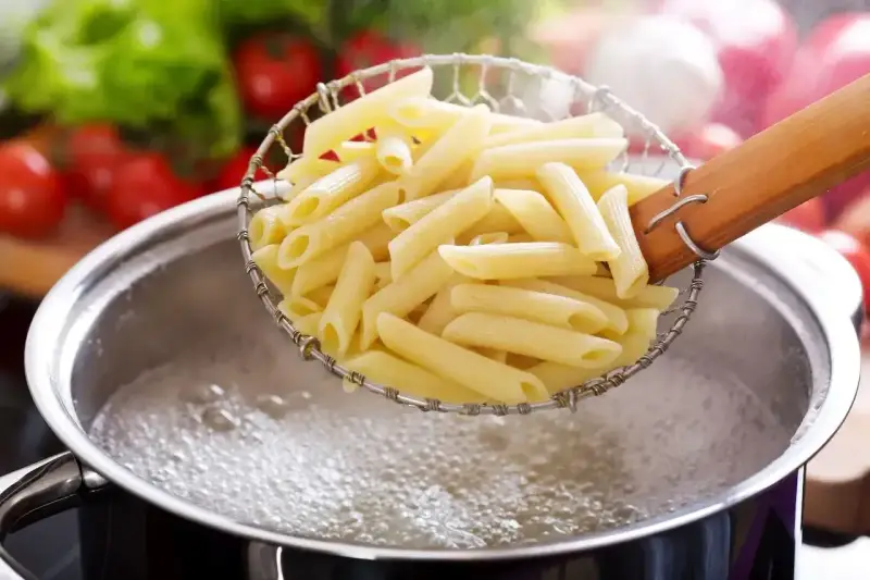 Penne makaron al dente, właśnie wyjęte z wrzątku, gotowe do sosu.